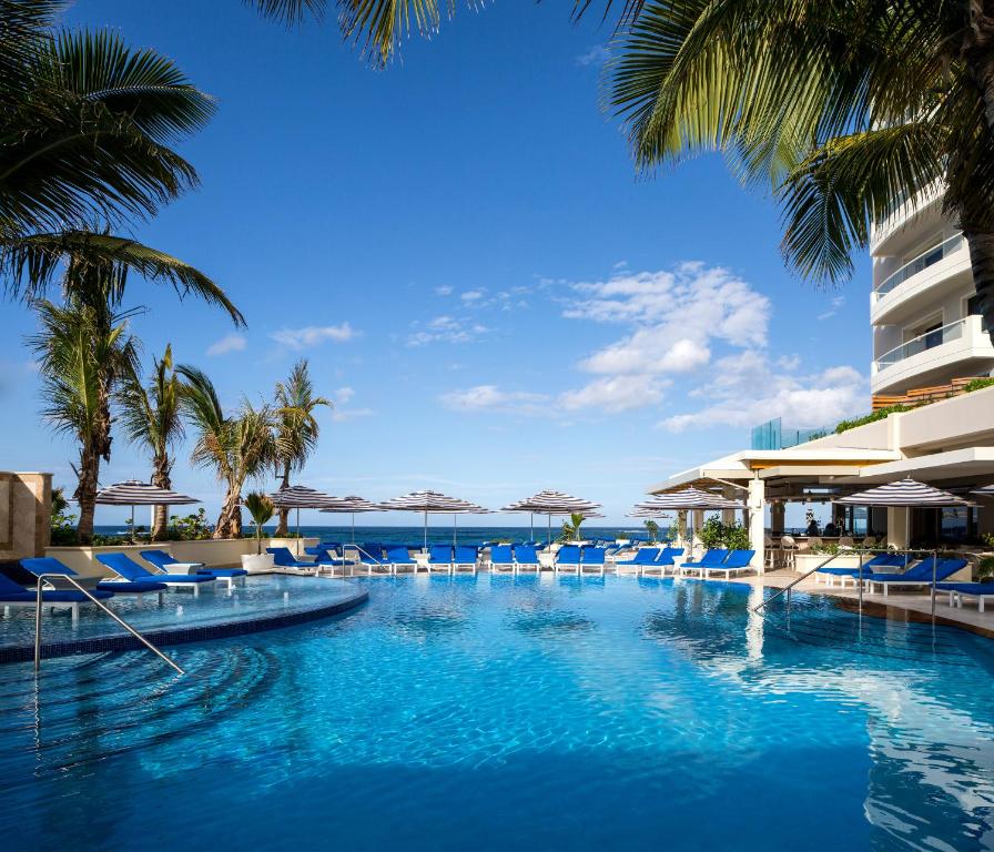 a swimming pool with blue chairs and palm trees at Condado Vanderbilt Hotel in San Juan