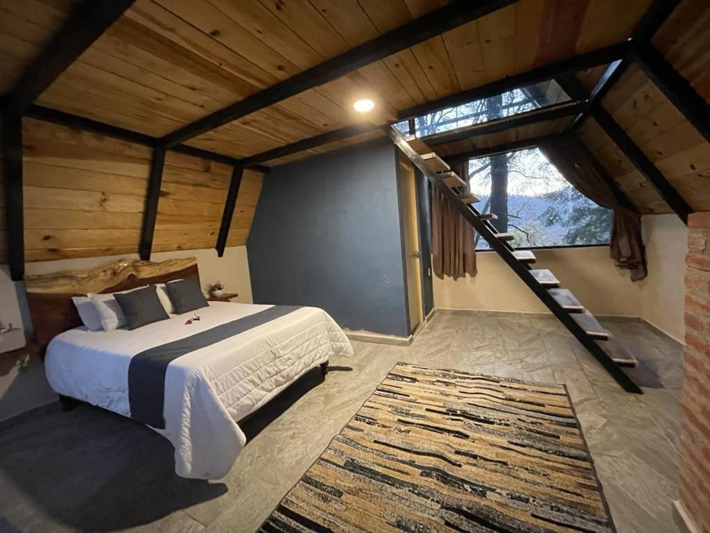 a bedroom with a large bed and a staircase at Portocielo Cabin in La Marquesa
