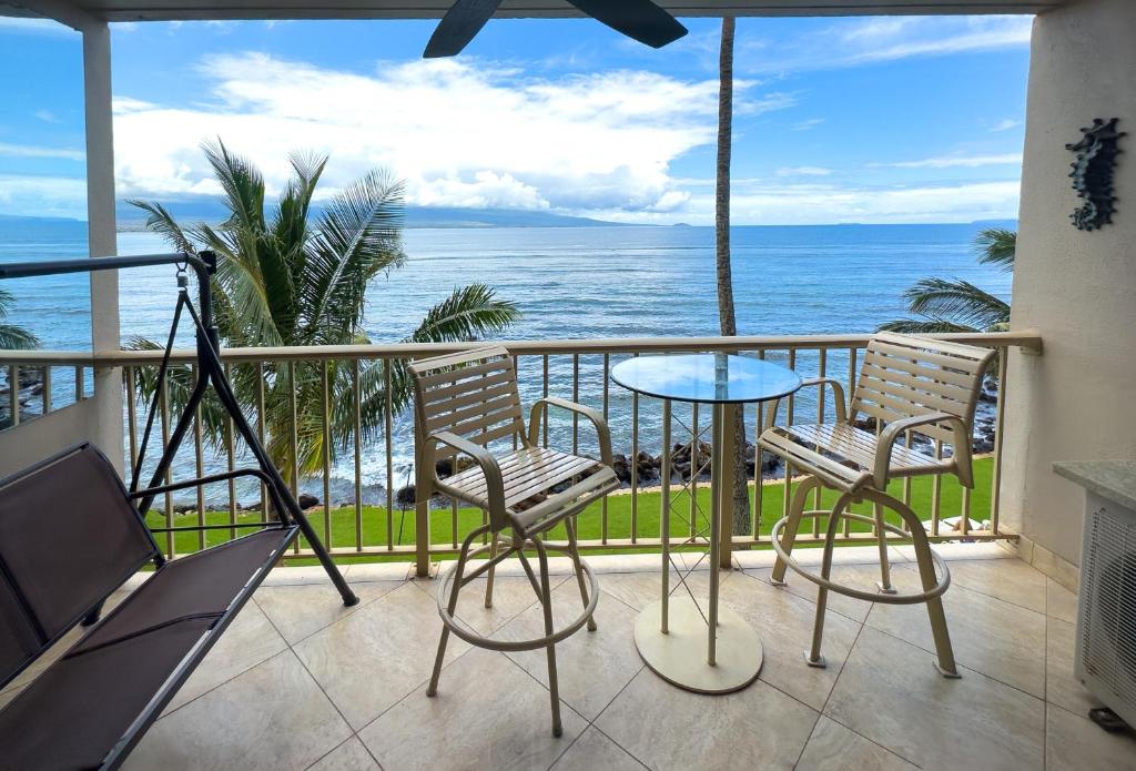 einen Balkon mit einem Tisch, Stühlen und Meerblick in der Unterkunft Maalaea Harbor-Oceanfront 2 Bedroom/2 Bath in Wailuku