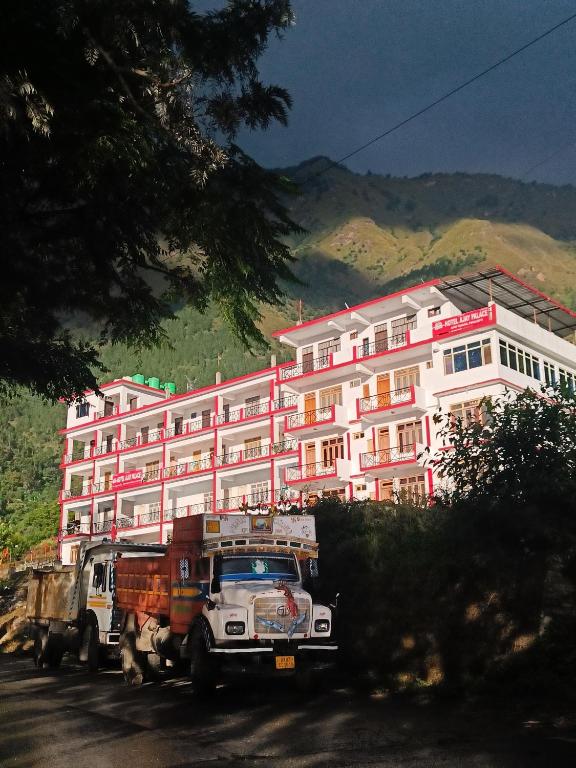 two dump trucks parked in front of a large building at Hotel Ajay Palace in Pīpalkoti