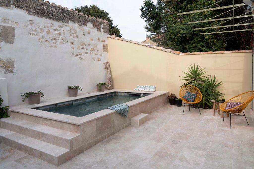 - une piscine sur une terrasse avec des chaises et une table dans l'établissement maison entière de village Fontvieille avec piscine, à Fontvieille