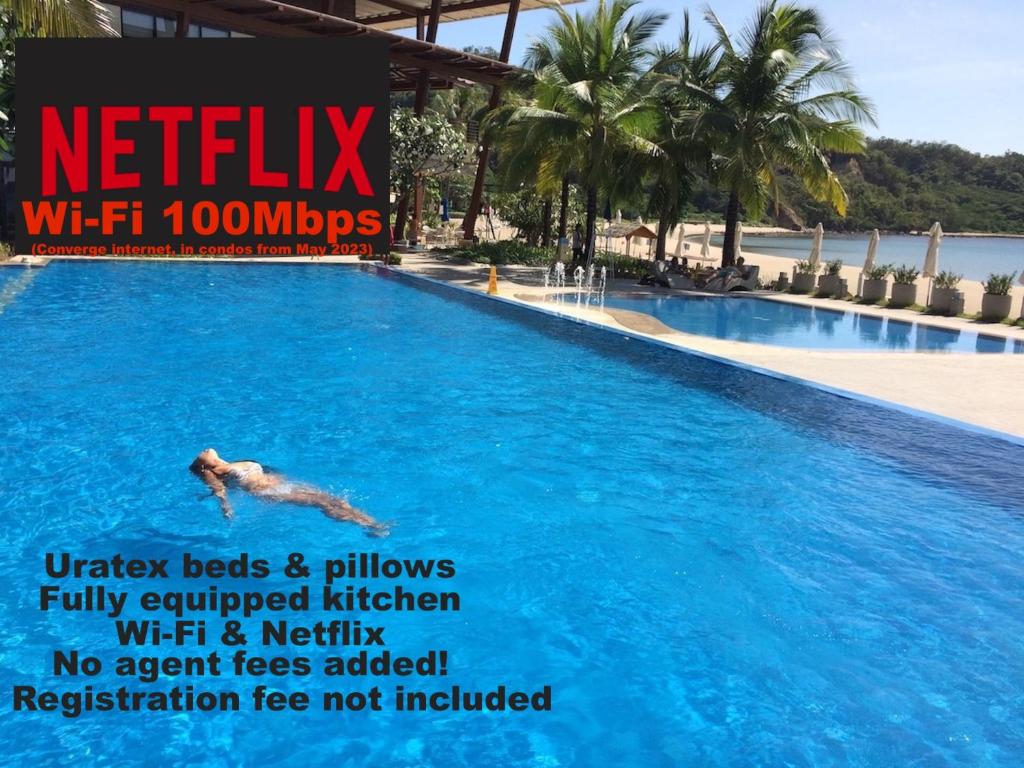 un homme nageant dans une grande piscine dans l'établissement Beach condos at Pico de Loro Cove - Wi-Fi & Netflix, 42-50''TVs with Cignal cable, Uratex beds & pillows, equipped kitchen, balcony, parking - guest registration fee is not included, à Nasugbu