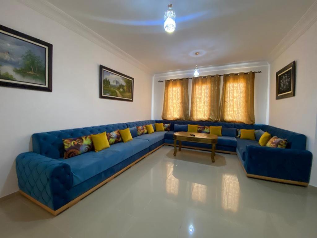 ein Wohnzimmer mit einem blauen Sofa und gelben Kissen in der Unterkunft complexe al massira imm 13 n 6 etg 2 in Fnideq