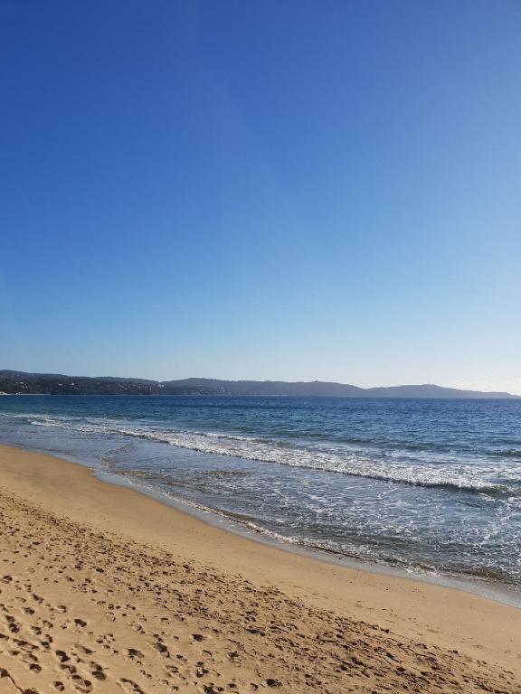 une plage de sable avec l'océan en arrière-plan dans l'établissement Superbe appartement cosy vue mer pieds dans l’eau, à Cavalaire-sur-Mer