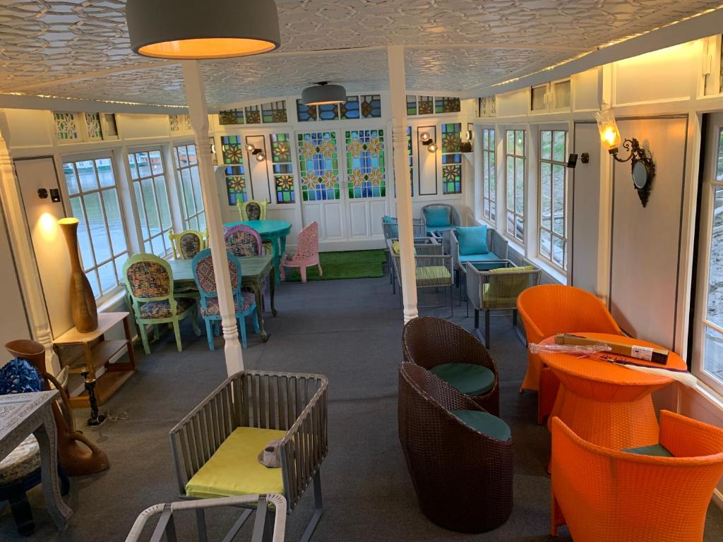 un restaurante con sillas coloridas, mesas y ventanas en Messiah’s Ark, en Srinagar