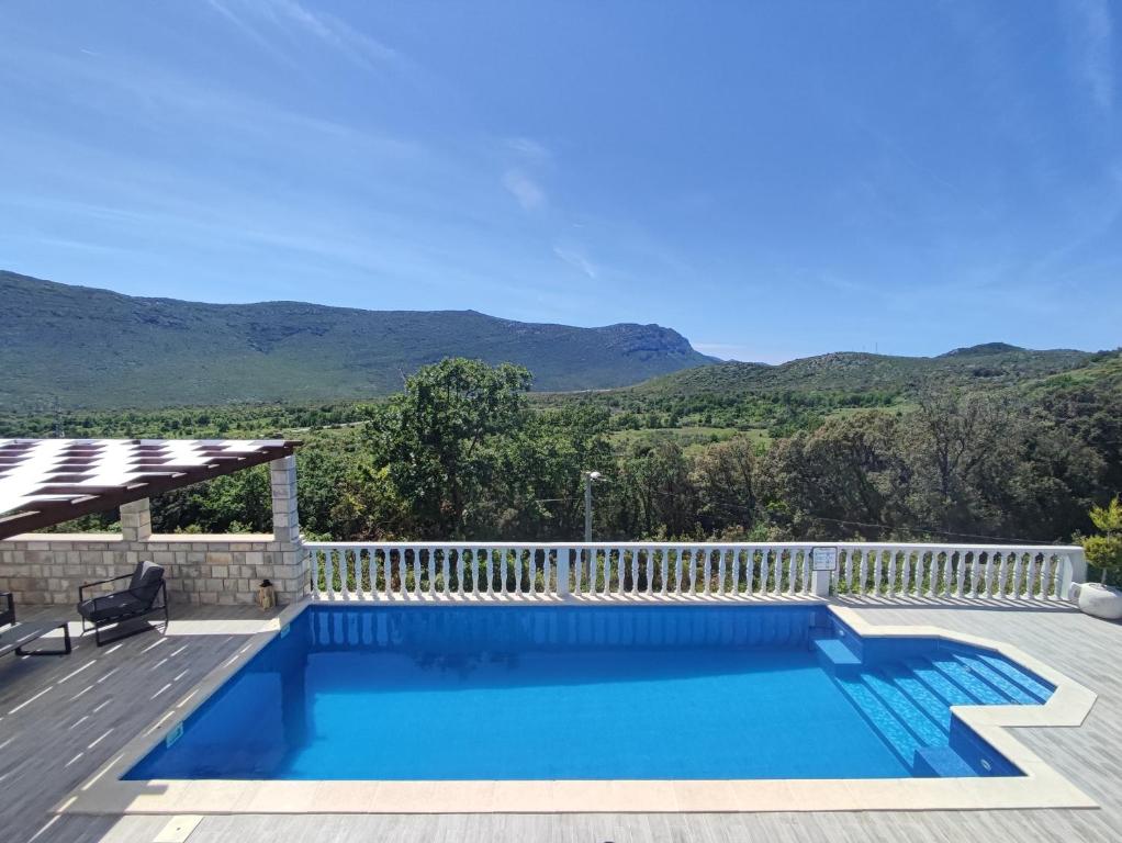 a swimming pool with a fence and mountains in the background at Sunny Hill in Ston
