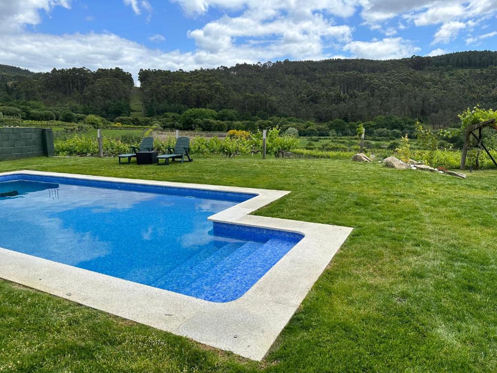uma piscina no meio de um jardim relvado em Casa La Antigua Escuela em Mondariz