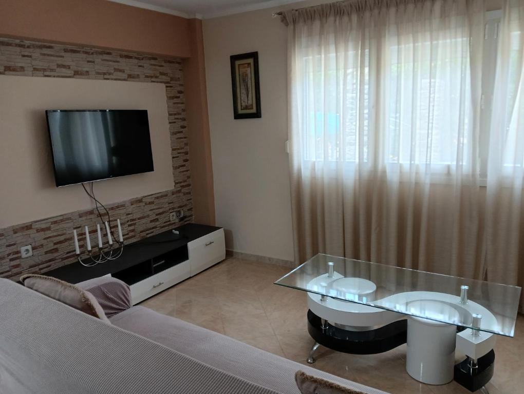 a living room with a tv and a glass table at Tamara in Kavála