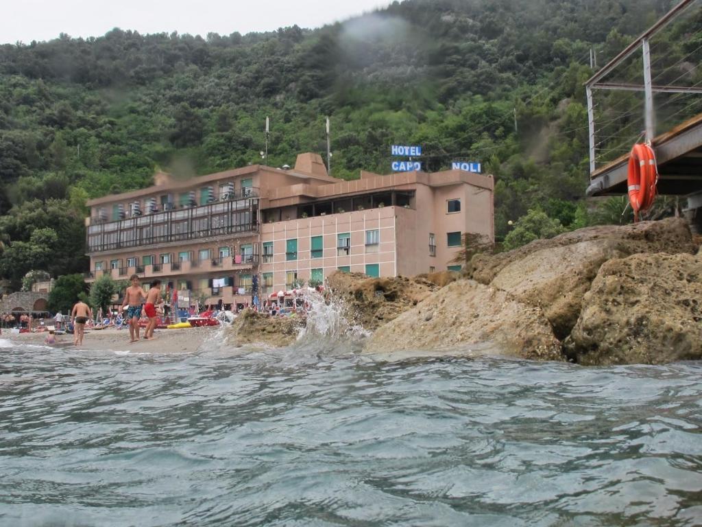een hotel op het strand met een lichaam water bij Hotel Capo Noli in Noli