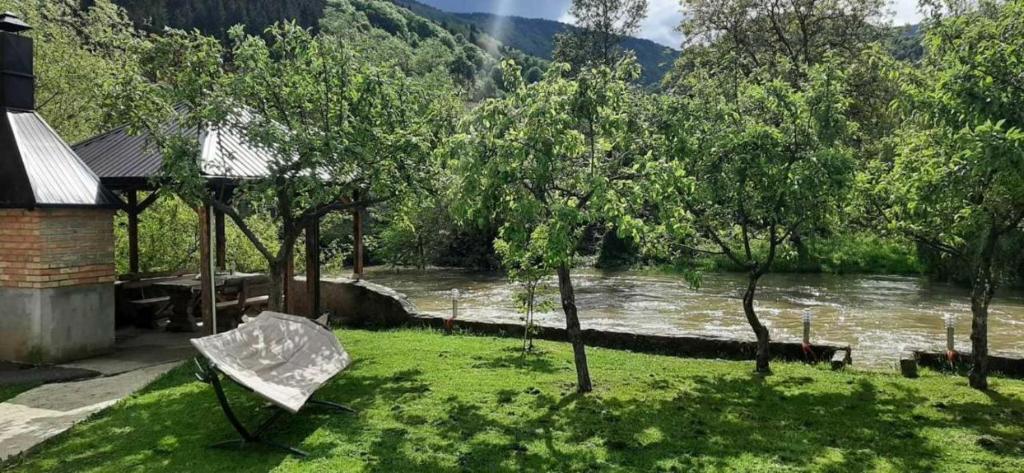 a bench in the grass next to a river at Apartman Vrbas in Jajce