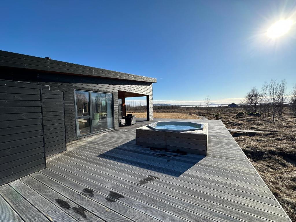 una terraza de madera con bañera de hidromasaje. en Luxury and Modern Cabin on the Golden Circle, en Miðdalur