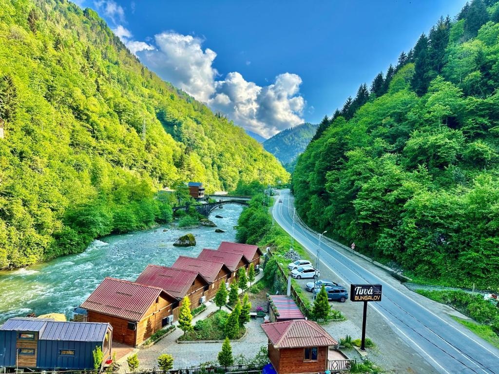 a river with a bunch of buildings next to a road at TUVA VİLLA Bungalov in Çamlıhemşin