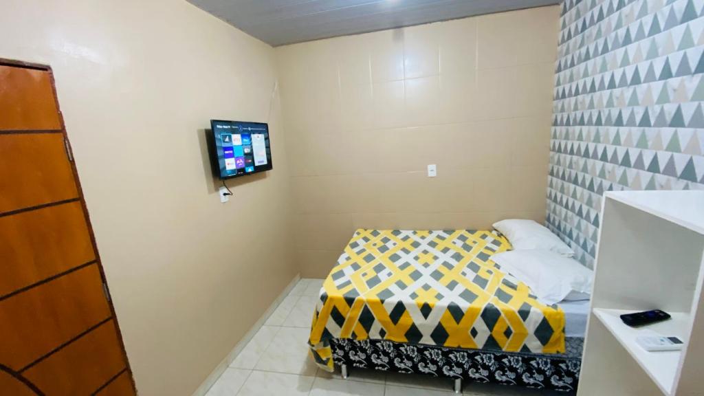 Apartamento 3 Aconchegante São Jorge في ماناوس: غرفة صغيرة بها سرير وتلفزيون