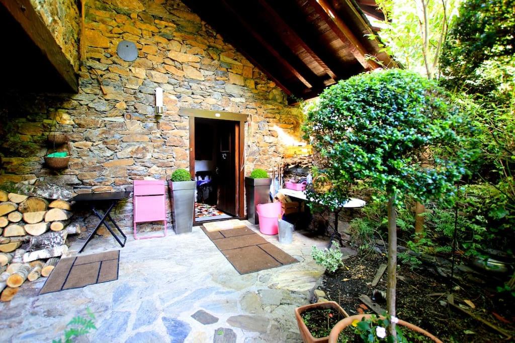 un edificio de piedra con un patio con sillas rosas en Place of charm and tranquility, en Ordino