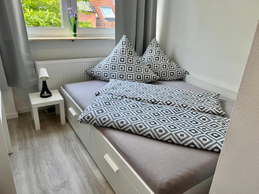 a bed with pillows on it in a small room at Nujen- Hotel und Apartment Stuttgart Zuffenhausen in Stuttgart