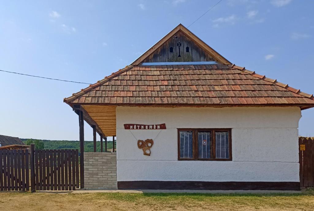una pequeña casa blanca con techo marrón en Két Kerék Vendégház, en Patvarc