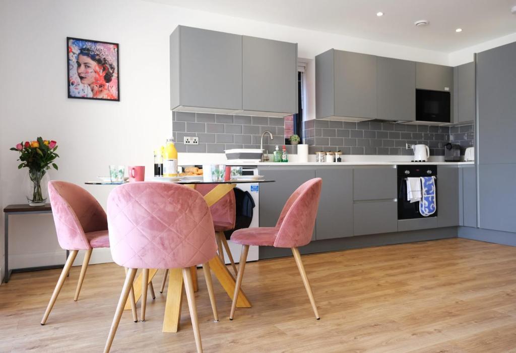 cocina con sillas rosas y mesa en Modern one Bedroom Apartment in Ealing Common en Londres