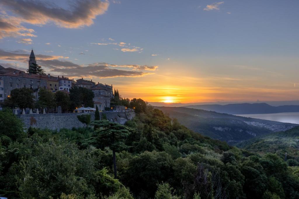 una ciudad en una colina con la puesta de sol en el fondo en Canova Apartment en Labin