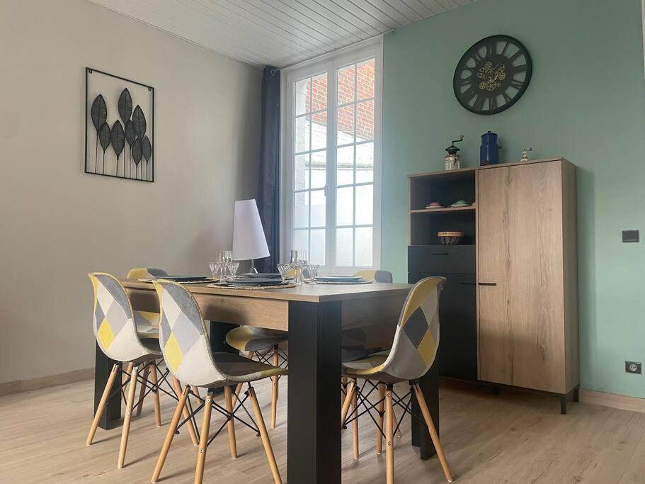 comedor con mesa con sillas y reloj en Maison à 2 pas du centre ville, en Péronne