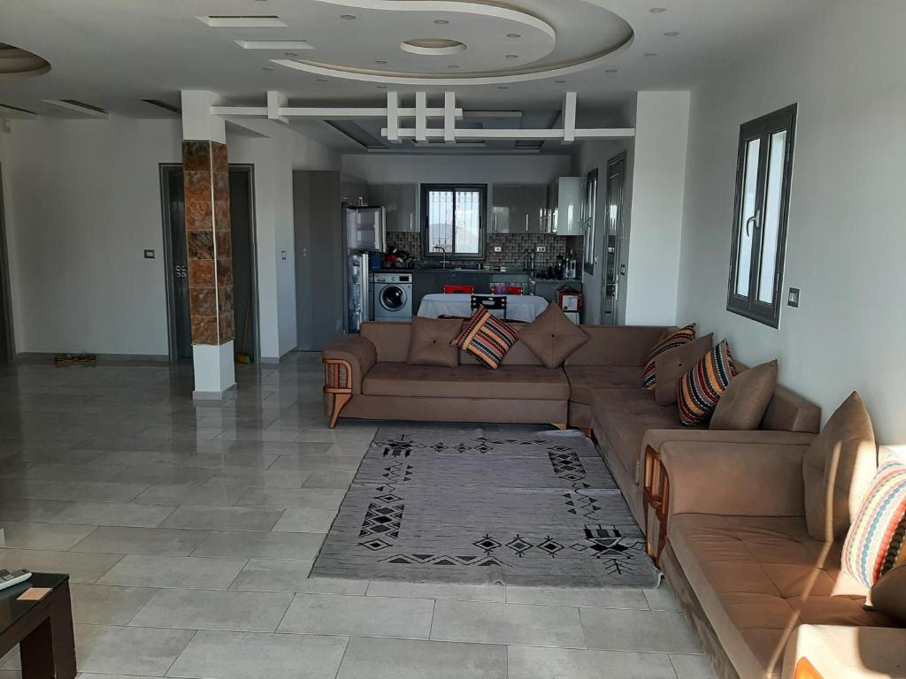 a living room with a brown couch and a kitchen at Villa de charme in Mezraya