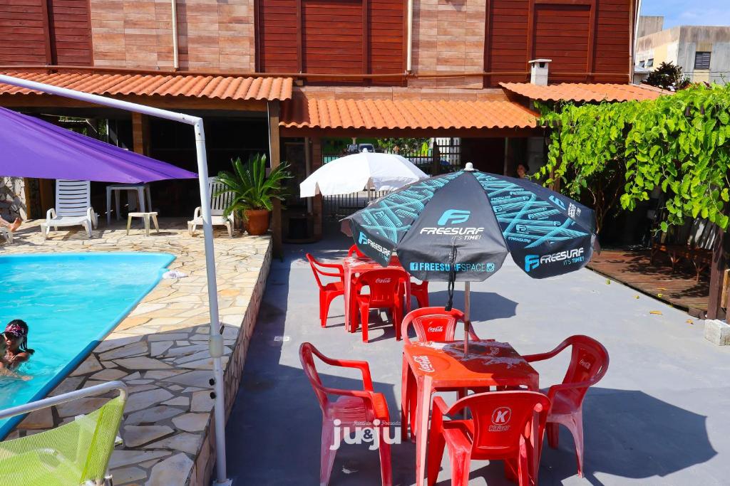 a group of chairs and umbrellas next to a pool at Recanto Pousada JU&JU com piscina COMPARTILHADA in Pontal do Paraná
