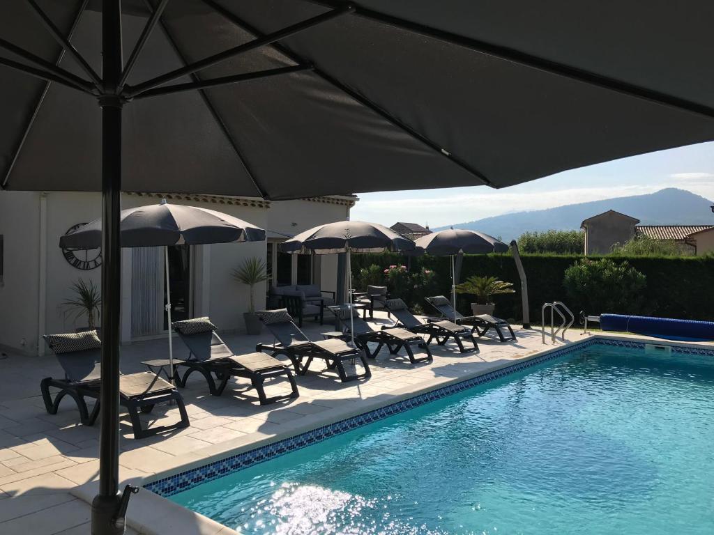basen z krzesłami i parasolami oraz grupa stołów i krzeseł w obiekcie Villa Jamy Roaix avec piscine w mieście Roaix