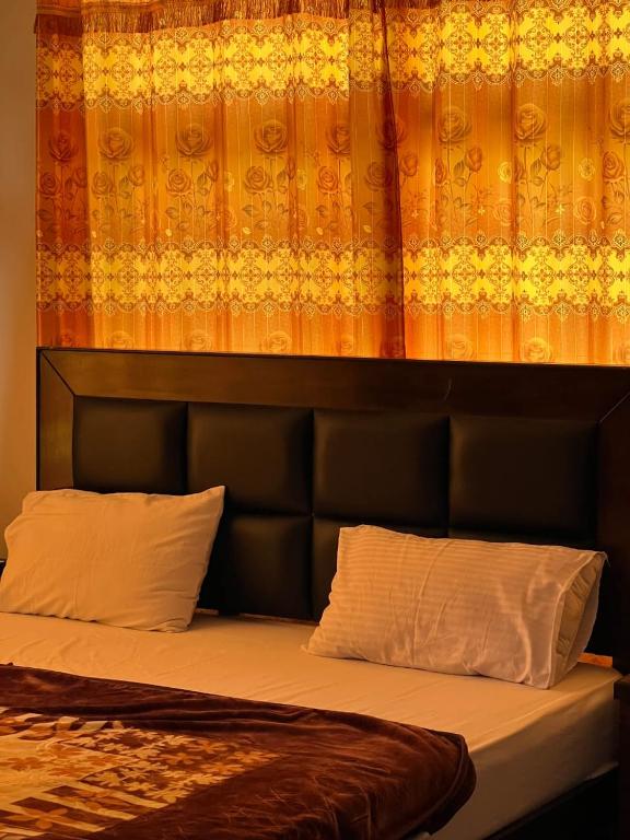 a bed with a black headboard and two pillows at Royal Resort Skardu in Skardu