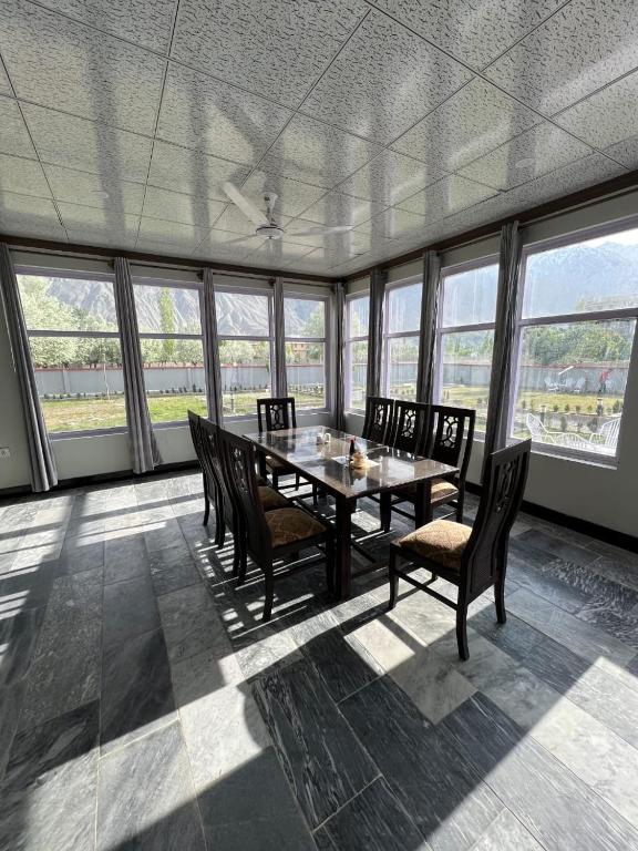 a dining room with a table and chairs and windows at Royal Resort Skardu in Skardu