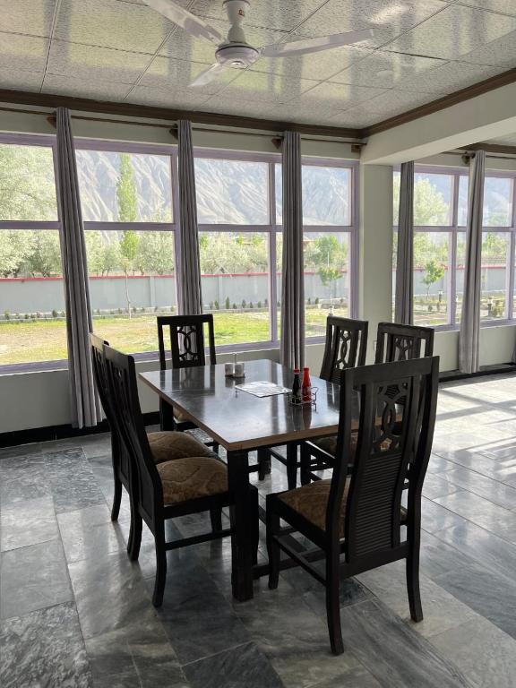 a dining room with a table and chairs and windows at Royal Resort Skardu in Skardu