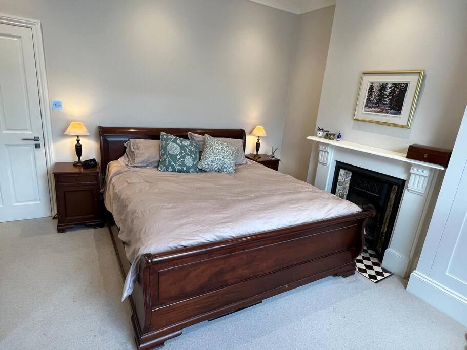 - une chambre avec un lit avec deux lampes et une cheminée dans l'établissement Four Bedroom modern Victorian Wandsworth House, à Londres