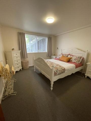 a bedroom with a white bed and a window at Westland Apartment in Dunedin