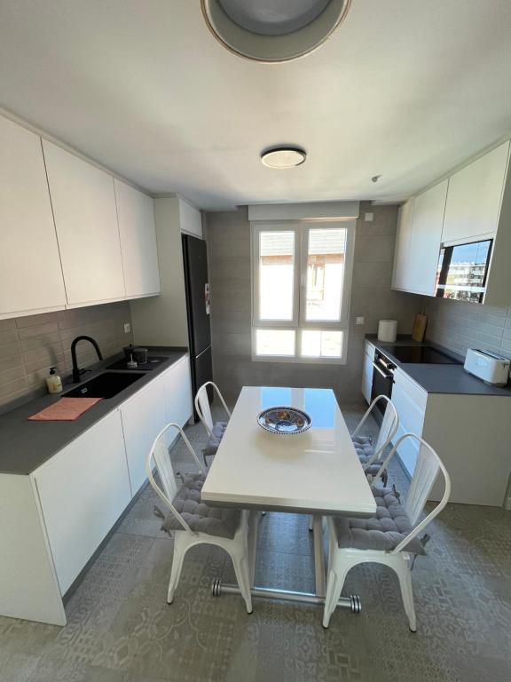 eine Küche mit einem Tisch und Stühlen in einer Küche in der Unterkunft Apartamento Recién Reformado en Somo junto iglesia in Somo