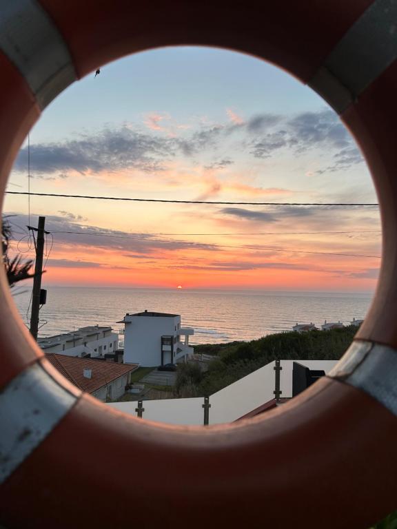 a view of the ocean through a round window at Mãe Home Foz in Foz do Arelho