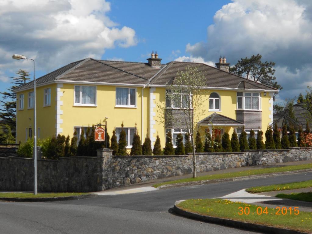 a yellow house with a stone retaining wall at The Yellow House B&B in Navan