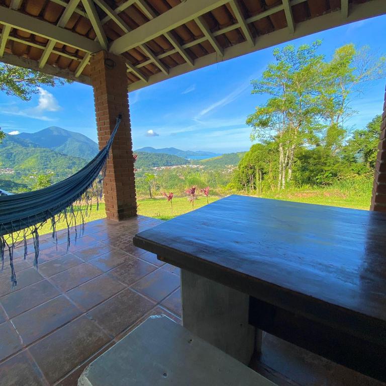 a hammock on the porch of a house with a view at Chácara Palma in Ubatuba