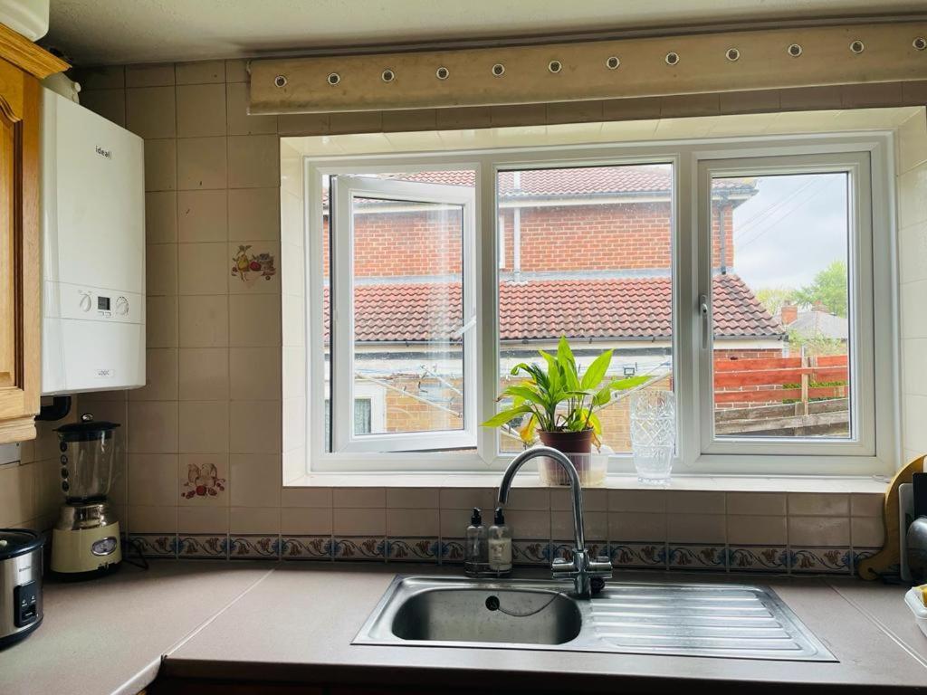 a kitchen with a sink and two windows at Rowan House Rotherham in Rotherham