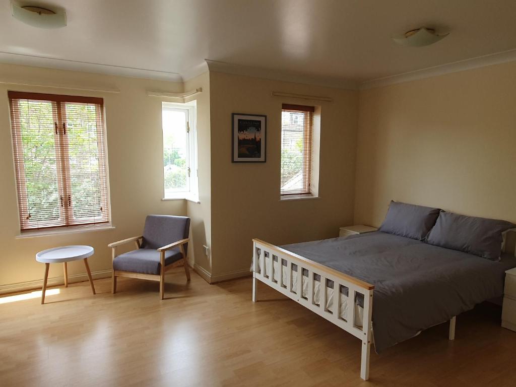 een slaapkamer met een bed, een stoel en ramen bij Spacious Room in Leafy, Quiet N4 in Londen