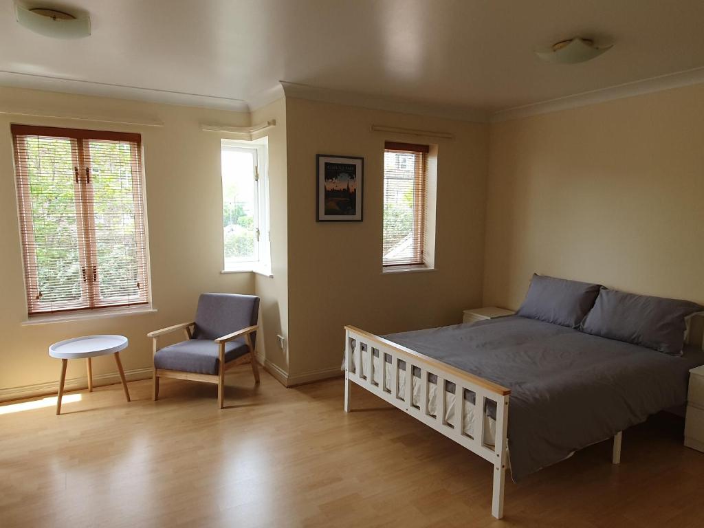 a bedroom with a bed and a chair and windows at Spacious Room in Leafy, Quiet N4 in London