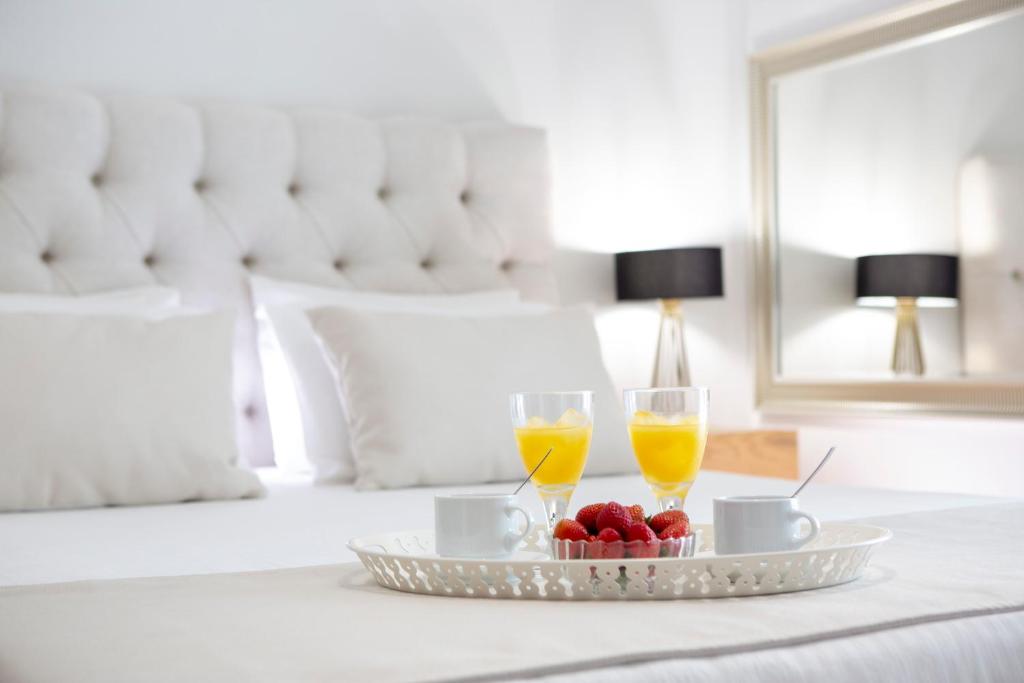 a tray with two glasses of orange juice and fruit on a bed at Adria Luxury Apartments in Nydri