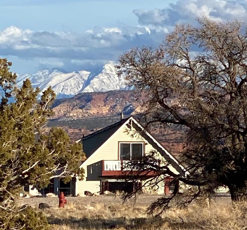 a white house with snow covered mountains in the background at Sandcreek Cottage / Fabulous Views on Five Acres in Torrey