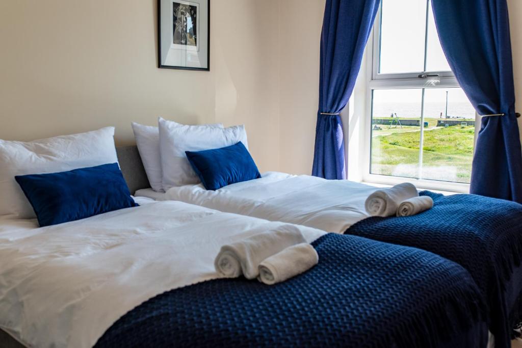 two beds in a room with blue curtains and a window at Serene Sands in Felixstowe