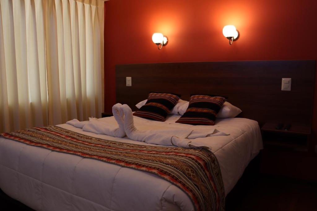 a bedroom with a large bed with white sheets and pillows at Casa del Escultor in Cusco