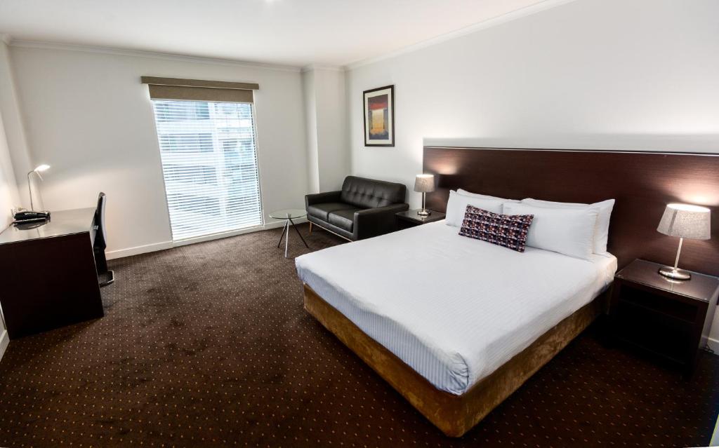 um quarto de hotel com uma cama e uma cadeira em Atlantis Hotel Melbourne em Melbourne