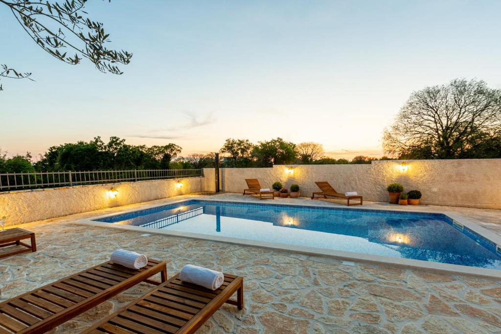 Seven Olives Guest House with heated pool near Krka waterfalls في Planjane: مسبح به صالتين جلوس بجانب جدار