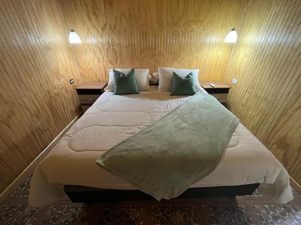 a bedroom with a large bed with green pillows at Refugio El Chucao in Hornopiren