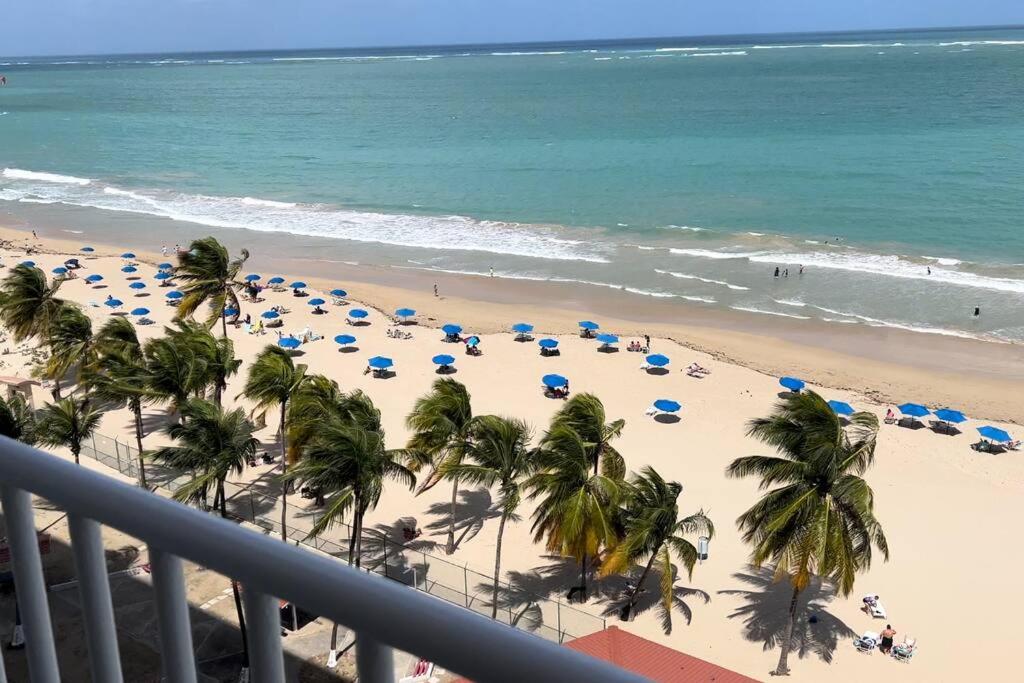 a beach with palm trees and umbrellas and the ocean at Ocean Front Condo in Isla Verde! in San Juan