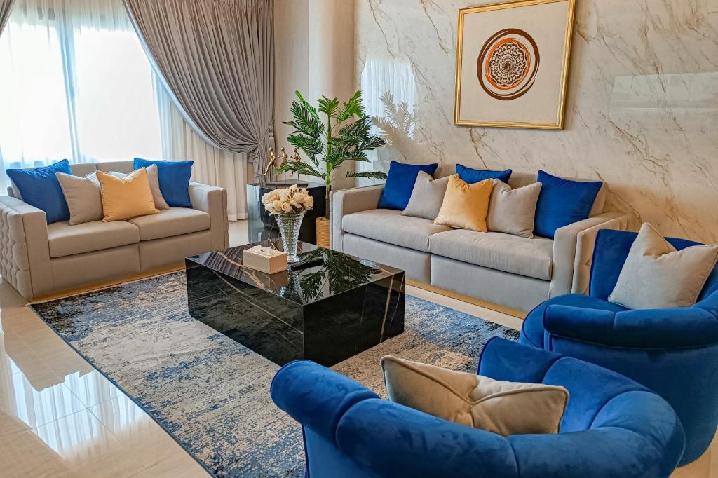 a living room with blue couches and a coffee table at HOOUD Apartments in Khor Fakkan