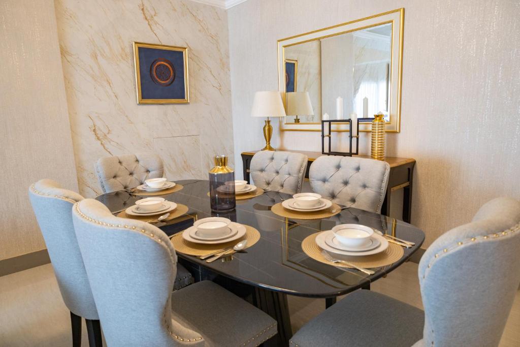 HOOUD Apartments في خور فكان: غرفة طعام مع طاولة زجاجية وكراسي زرقاء