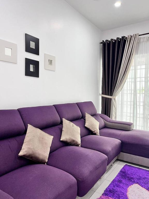 a living room with a purple couch with pillows at Raina Muslim Homestay Perlis in Arau