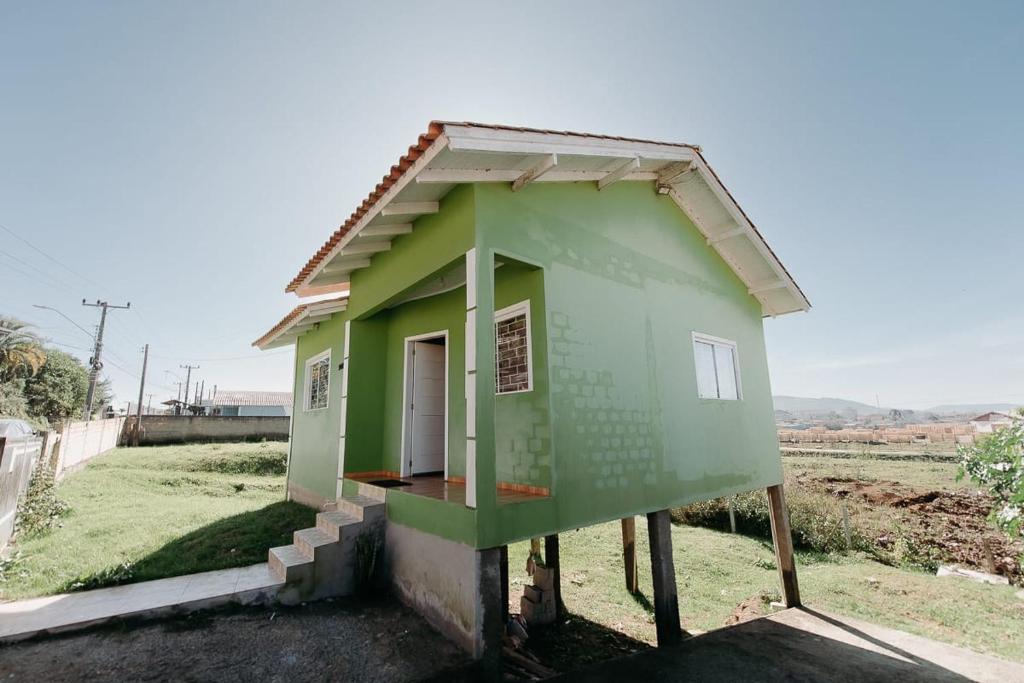 una pequeña casa verde sentada en la cima de un campo en casa em LAGES 2 km do centro LAGES, en Lages